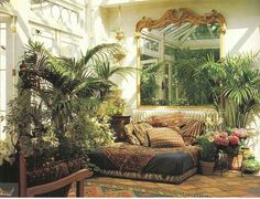 a living room filled with lots of potted plants next to a couch and mirror