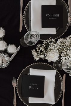 black and white place setting with silverware, flowers and napkins on the table