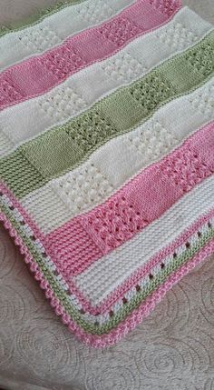 a crocheted blanket on top of a bed next to a white and pink pillow