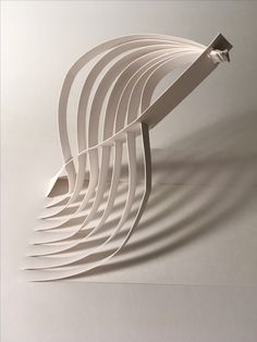 an abstract sculpture made out of paper on a white surface with shadows coming from it