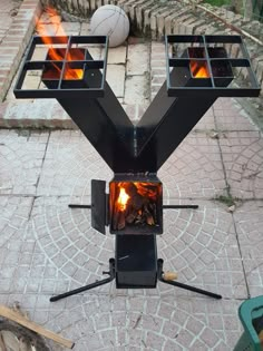 an outdoor stove with fire in it sitting on the side of a brick road next to a basketball hoop