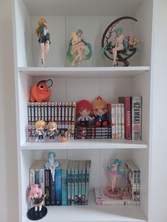 a book shelf filled with books and figurines on top of eachother