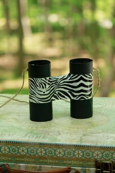 two black and white vases sitting on top of a table in front of trees