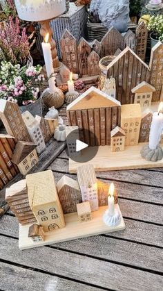 two wooden houses with candles on them sitting on a table next to flowers and other decorations