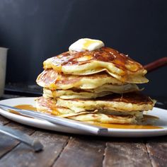 a stack of pancakes on a plate with syrup and butter being drizzled over them