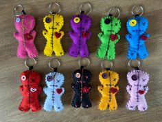 six different colored teddy bears are hanging from keychains on a table with wood flooring