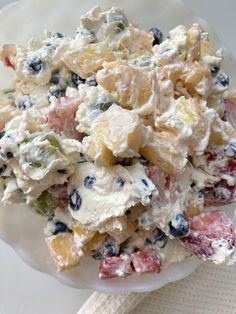 a white plate topped with fruit salad on top of a table next to a napkin