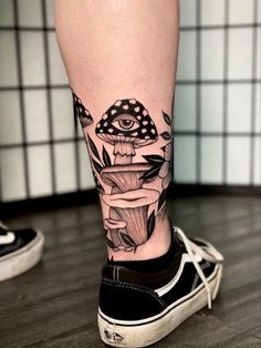 a person's leg with a mushroom tattoo on it and an eye in the background