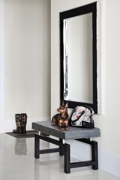 a small dog sitting on top of a bench next to a mirror and handbag