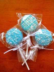 three lollipops wrapped in plastic wrappers on a wooden table with white sprinkles