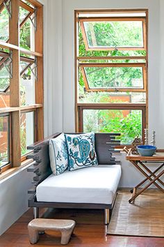 a living room filled with furniture and windows next to a wooden floor covered in wood planks