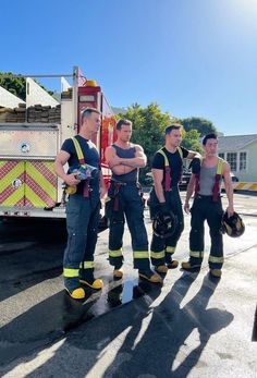 four firefighters standing in front of a fire truck