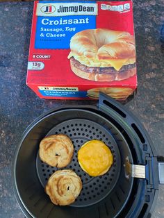 an open box of cheese and two pastries on a black pan with the lid down