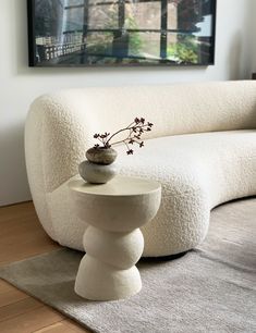 a white couch sitting next to a table with a vase on it's end