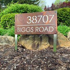 a sign that reads 38707 biggs road in front of some bushes and rocks