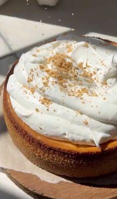 a cake with whipped cream and sprinkles sitting on top of a wooden board