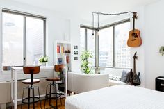 a bedroom with a guitar hanging from the ceiling next to two chairs and a bed