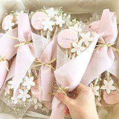 a person is holding onto some cookies in a box with flowers on them and ribbons