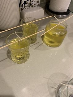 three glasses filled with yellow liquid sitting on top of a counter next to a plate