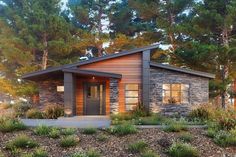 a small house in the woods with trees and shrubs around it's front entrance