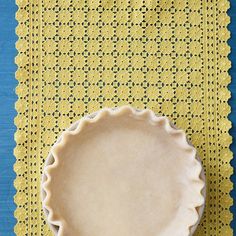 a pie crust sitting on top of a yellow placemat next to a blue table