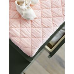 a pink quilted table with white shoes on it