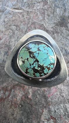 I have set a genuine turquoise cabochon in sterling and fine silver. The round stone is framed by a smooth triangular shadowbox setting. I have created this one-of-a-kind design by sawing, forming, soldering, and finishing the piece entirely by hand. The silver has been oxidized and polished to create a patina finish. This ring is US size 8.25 as sized on a standard US ring sizer. Turquoise: 14mm Be sure to see all photos and video for size and color reference. Triangle Ring, Sterling Silver Rings Turquoise, Artisan Rings, Patina Finish, Handmade Rings, Genuine Turquoise, Soldering, Turquoise Sterling Silver, Fine Silver