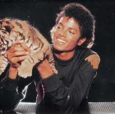 a man holding a tiger cub in his hands