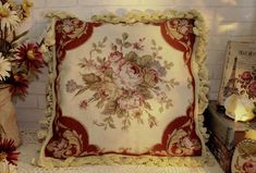 a decorative pillow sitting on top of a table next to some books and vases