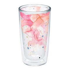 a glass with pink flowers painted on the side and dots in the bottom, sitting against a white background