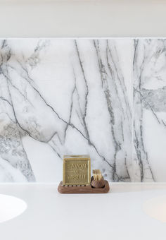 a bathroom with marble walls and white countertops, including a soap dispenser