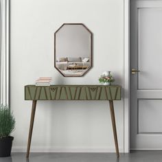 a green table with a mirror on it next to a potted plant and door