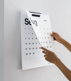 a person pointing to a calendar on a wall