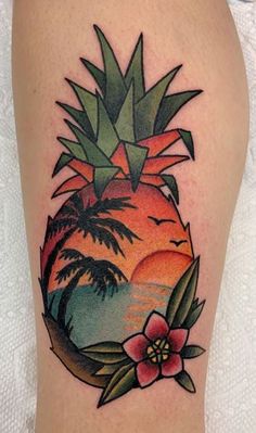 a pineapple tattoo on the thigh with flowers and leaves in front of an ocean sunset