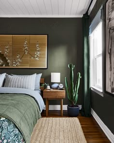 a bed room with a neatly made bed next to a window and a cactus plant