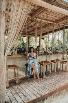 a woman sitting on a swing in front of a bar with wooden benches and tables