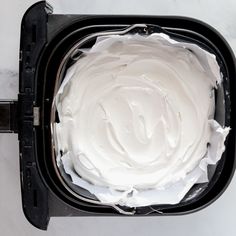 a black container filled with white frosting on top of a counter