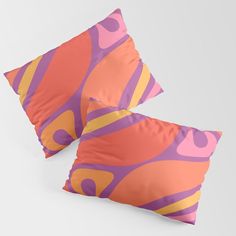 two orange and pink pillows sitting next to each other