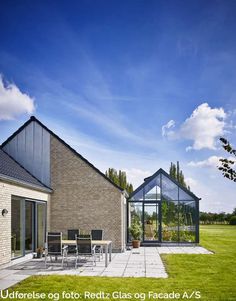 a house that has a glass roof and some chairs in the grass near by it