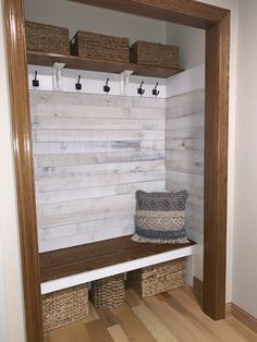 a wooden bench with baskets on it in front of a white wall and wood floor