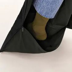 a person sitting in an umbrella with their feet propped up on the ground and wearing socks