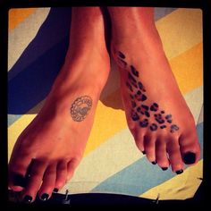 two feet with leopard print on them and one has a circle tattoo on the foot