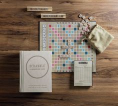 the scrabble board game is laid out on a wooden table next to its contents