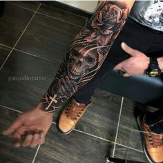 a man with a skull and roses tattoo on his arm