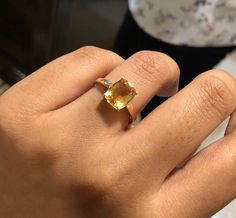 a close up of a person's hand wearing a ring with an orange stone