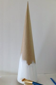 a white and brown cone shaped object sitting on top of a table next to a blue pen