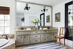 a large bathroom with two sinks, mirrors and a bathtub in the middle of it