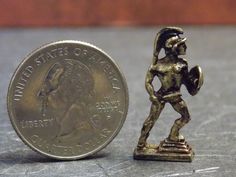 a tiny bronze figurine is next to a penny