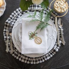 a table set for two with white plates and silverware, napkins and flowers