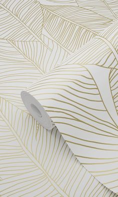 a white and gold wallpaper with wavy lines on the bottom, along with a roll of tape